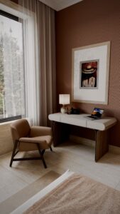 Design interior camera hotel de lux cu birou din nuc și blat crem, fotoliu caramel, tapet terracotta cu textură, tablou figurativ și lumină naturală Fabiano Interiors Amenajare realizată de Fabiano Interiors, expert design interior Oradea.